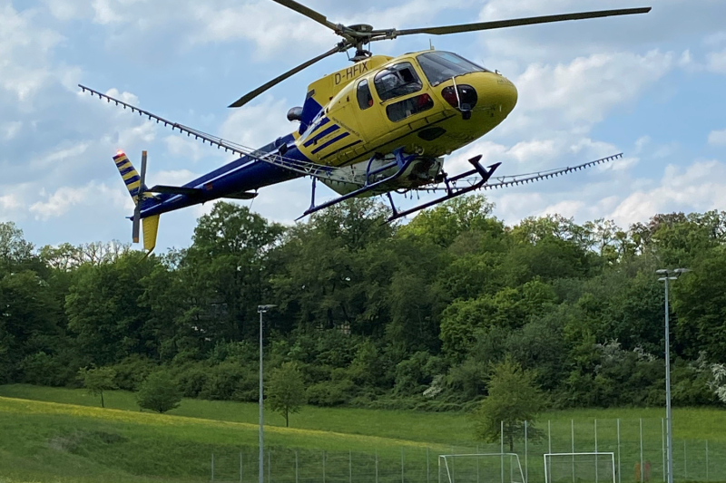 Hubschrauber startet über grüner Wiese.