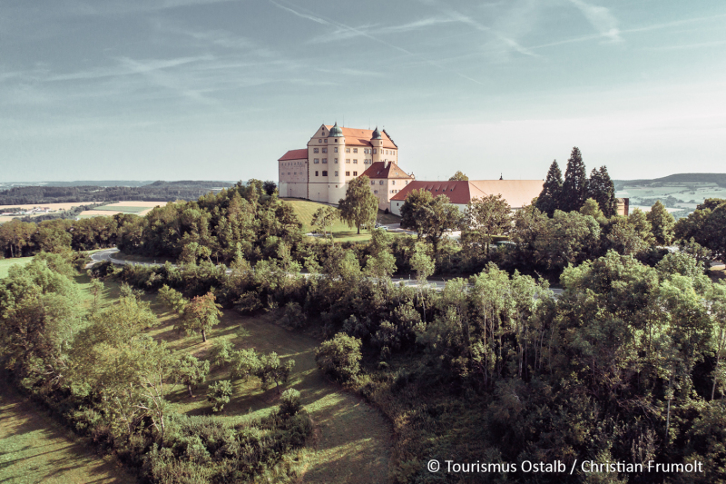 Mit Wald bewachsener Berg, darauf Schloss Kapfenburg